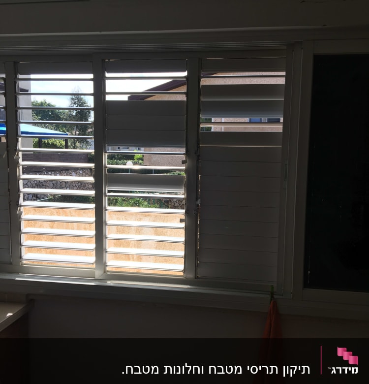 תריסים לבנים פתוחים למחצה עם נוף חיצוני